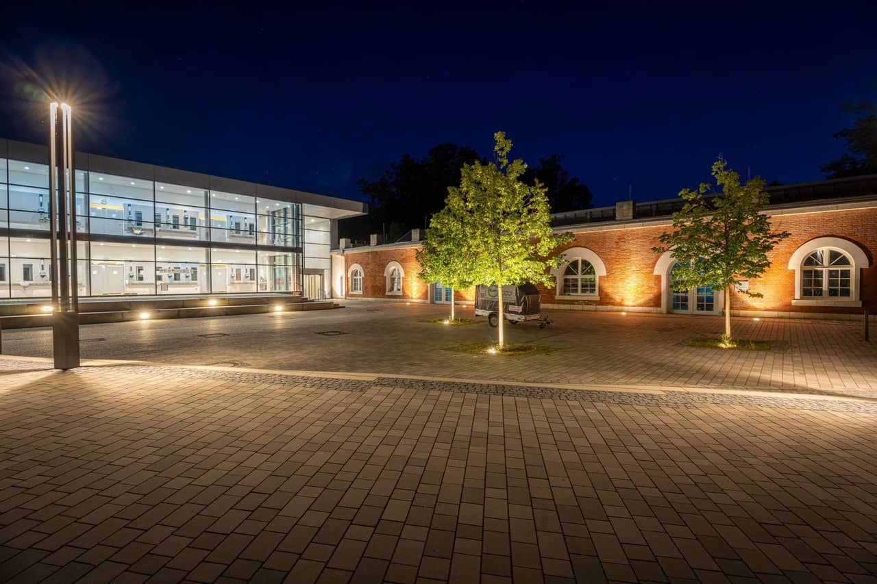gebäude im dunkeln mit beleuchtetem Platz davor.